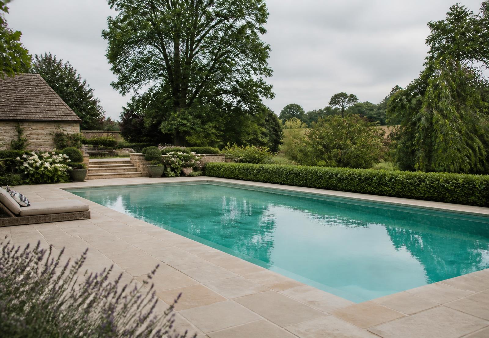 Finished in-ground swimming pool with stone coping in a UK country garden